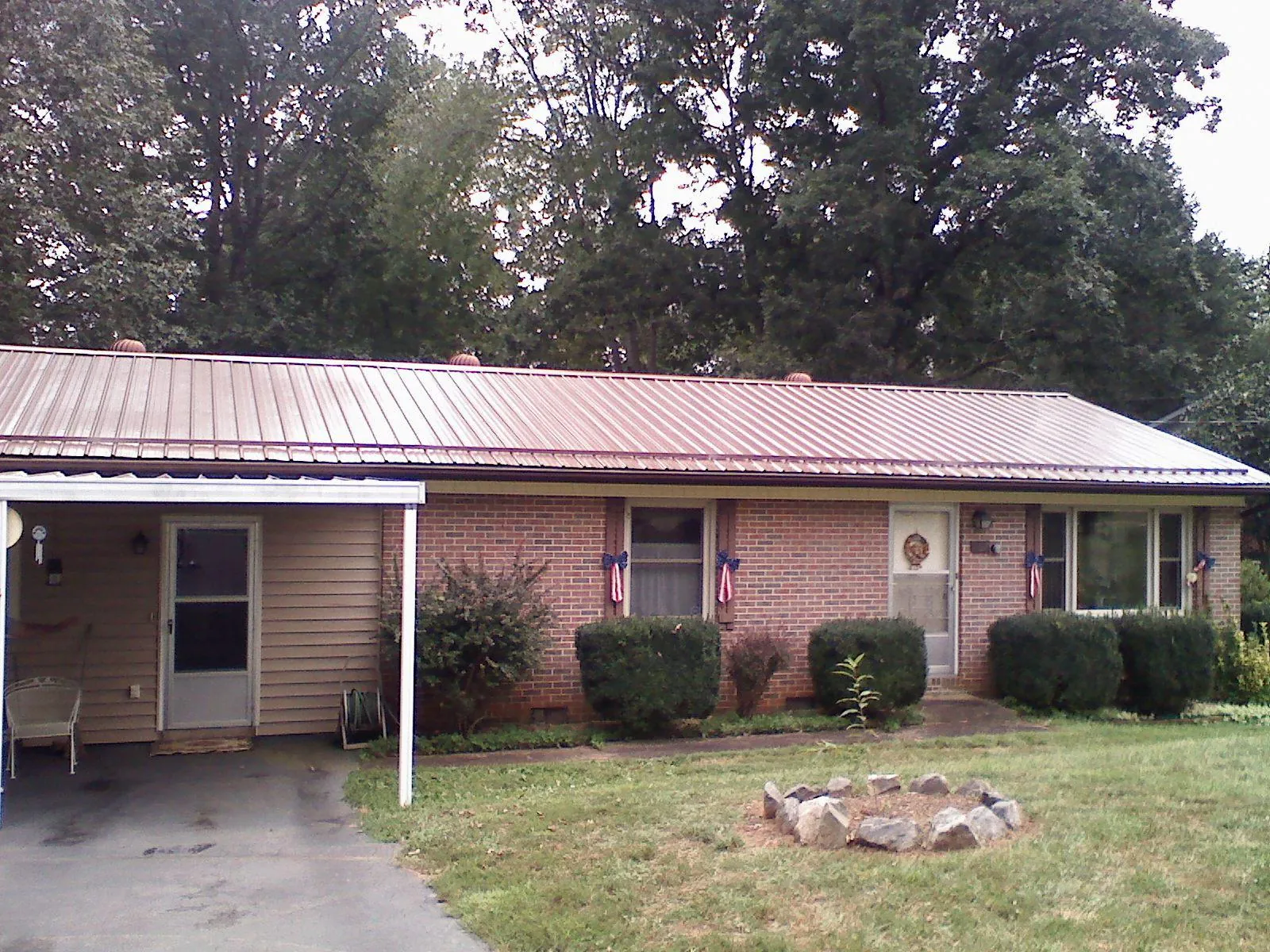 Bronze metal roof and carport on a brick ranch home — Roof Repair work by our crew in Saint Francis