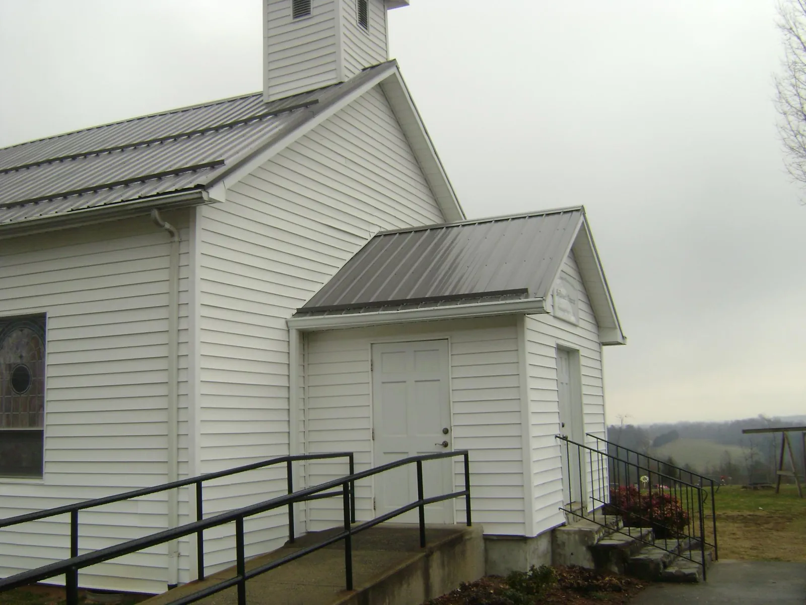 Gray metal roof on a white clapboard church with a steeple in Saint Francis